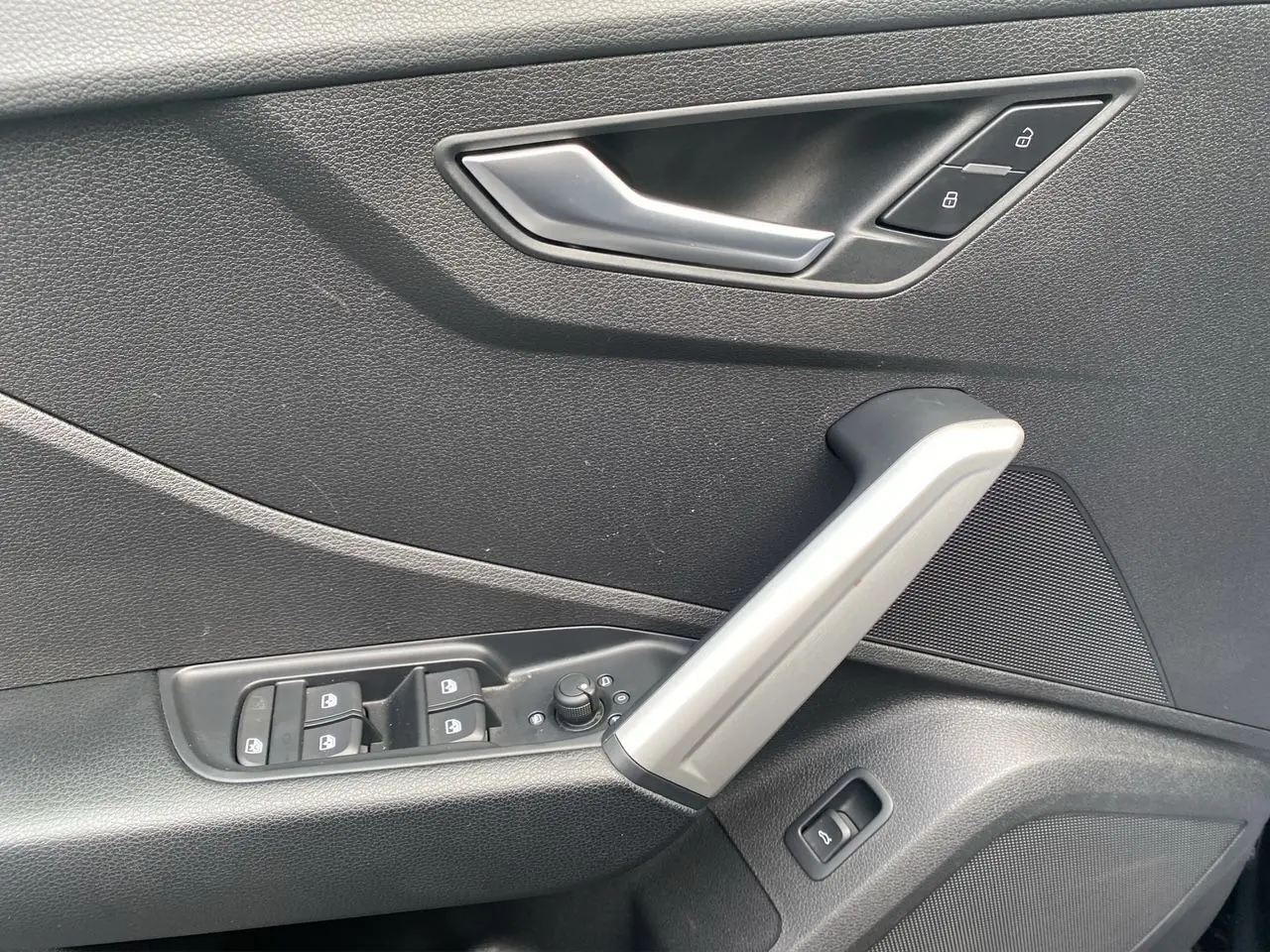Détail de la porte côté conducteur de l'Audi Q2 2023 noir Mito avec commandes de vitres et serrure intégrée.