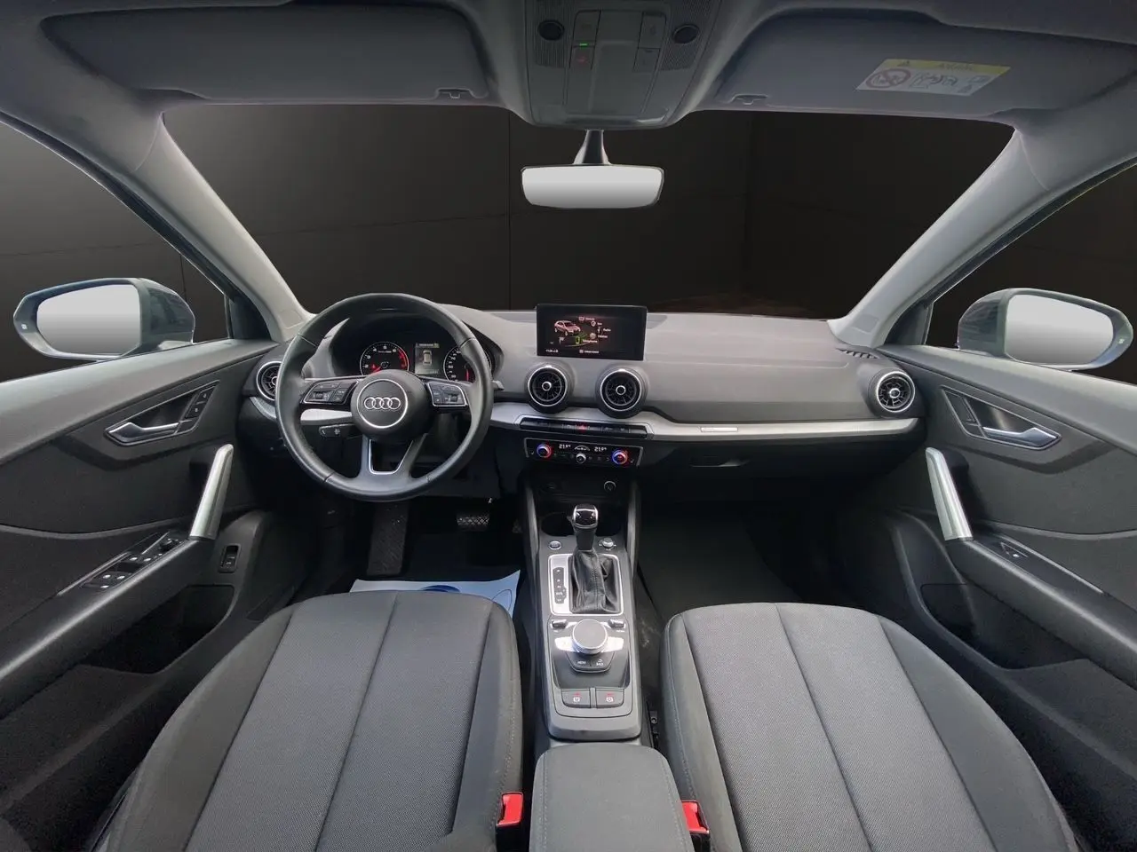 Vue intérieure avant de l'Audi Q2 35 TFSI S-Line 2023 avec tableau de bord noir et écran central GPS.