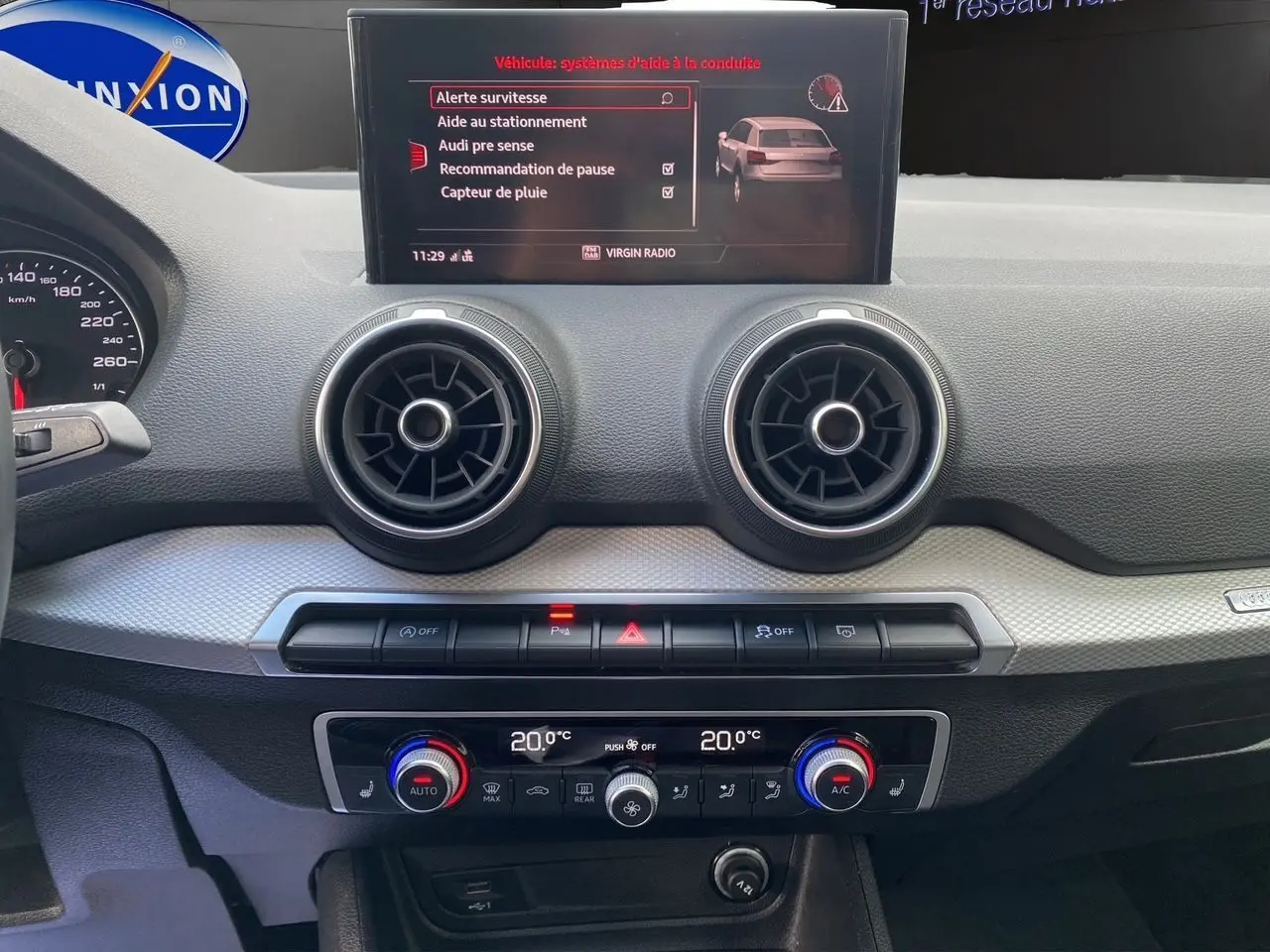 Tableau de bord de l'Audi Q2 35 TFSI 2023 avec écran central affichant les aides à la conduite et commandes climatisation.
