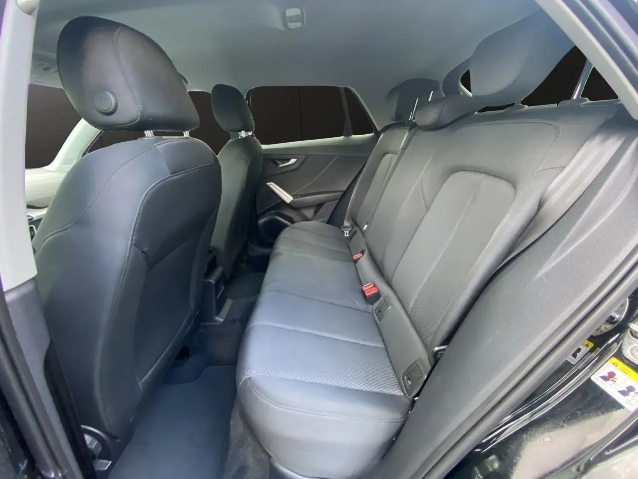 Vue intérieure arrière droite de l'Audi Q2 2023 avec sièges tissu noir et appuie-têtes intégrés.