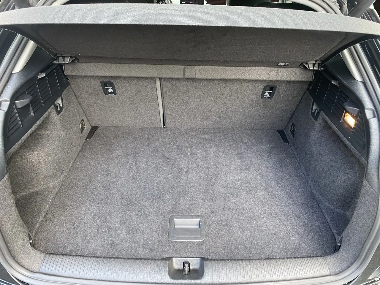 Coffre spacieux et propre de l'Audi Q2 noir mito, vue intérieure arrière avec éclairage latéral allumé.