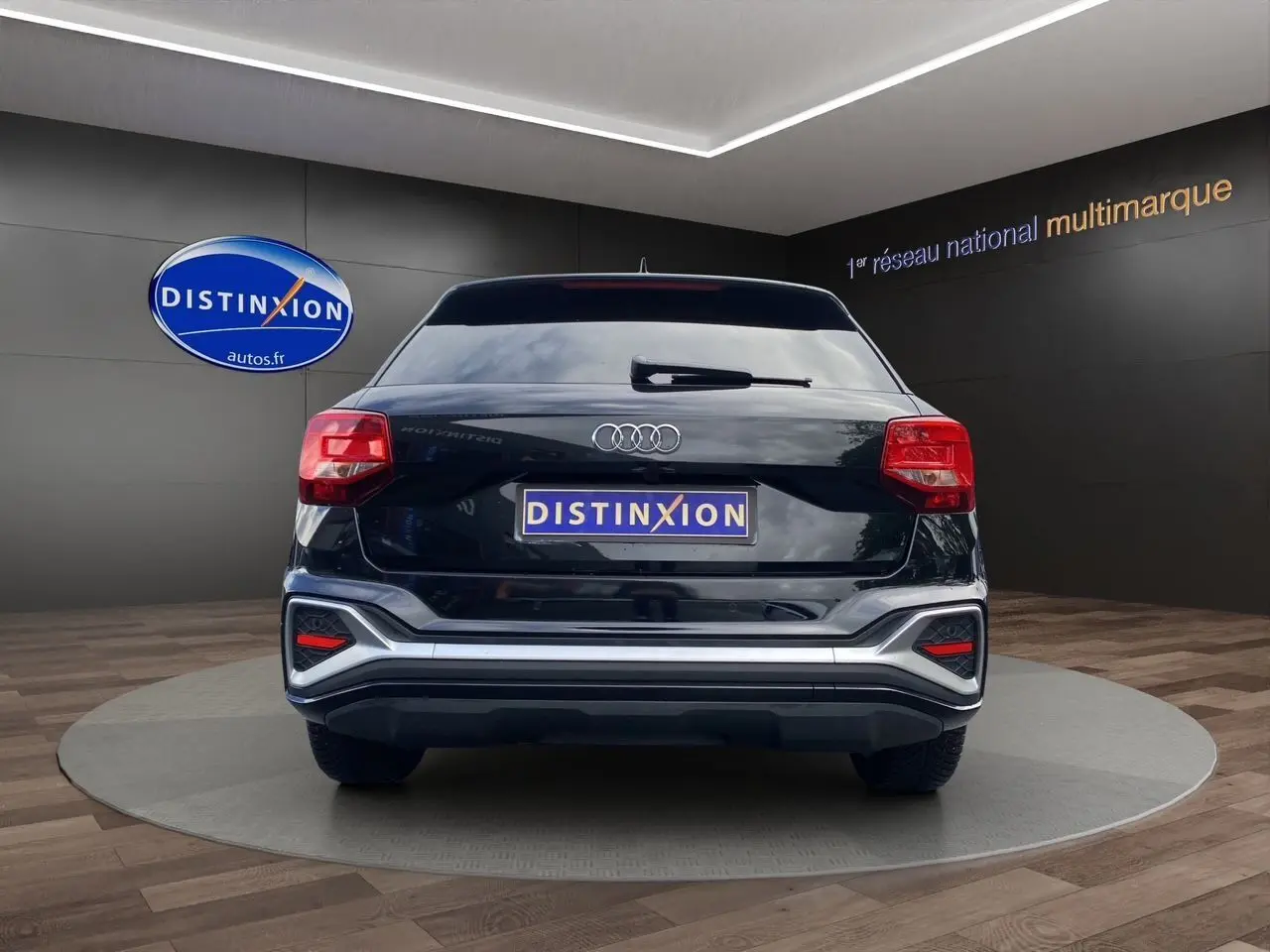 Vue arrière d'un Audi Q2 noir Mito avec hayon motorisé et feux arrière LED dans un showroom.