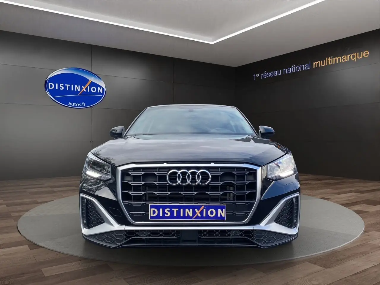 Vue frontale d'un Audi Q2 noir Mito avec calandre hexagonale et éclairage LED dans un showroom.