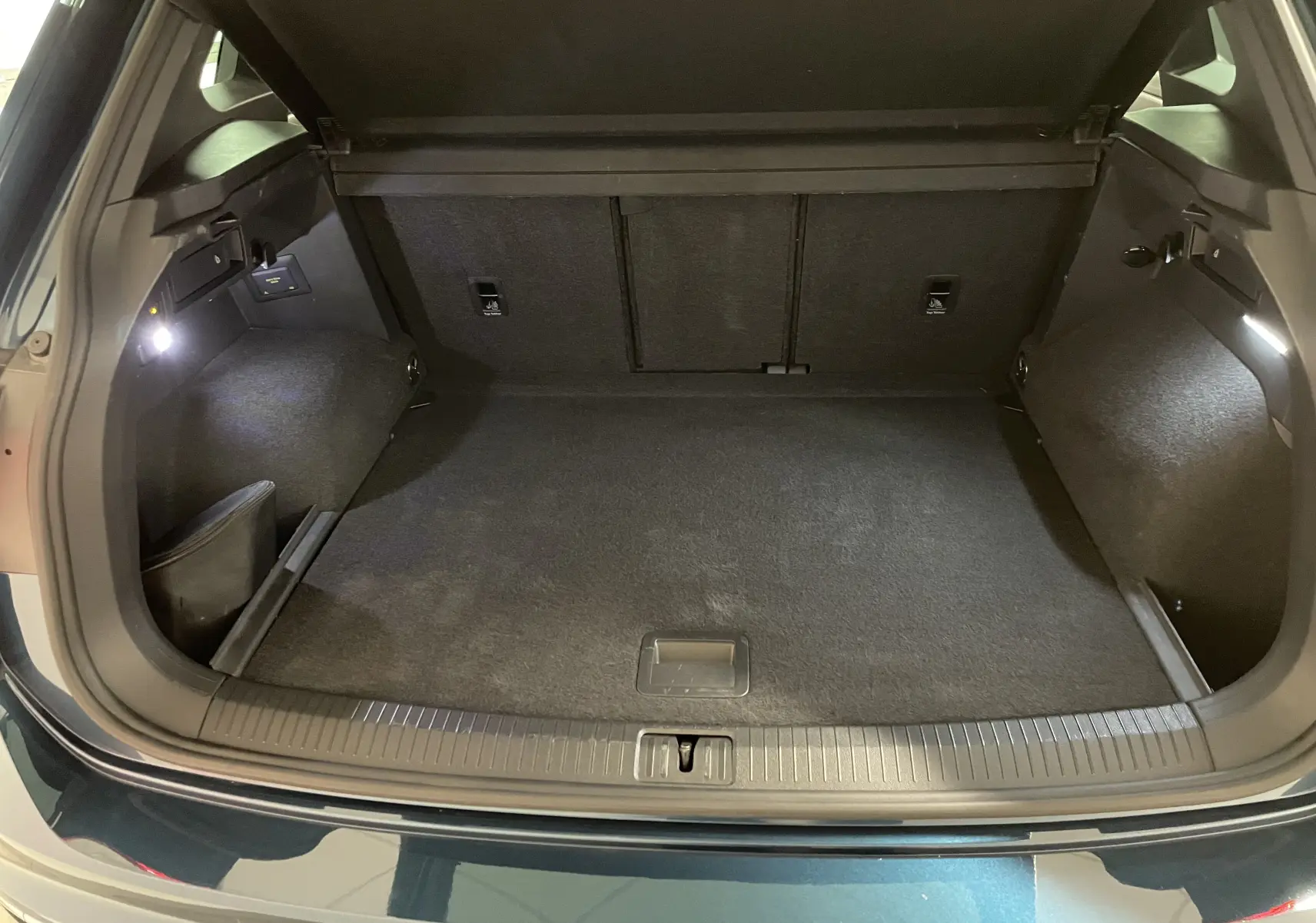 Coffre ouvert du Volkswagen Tiguan 2024 Nightshade Blue, montrant un espace de chargement propre et bien éclairé.