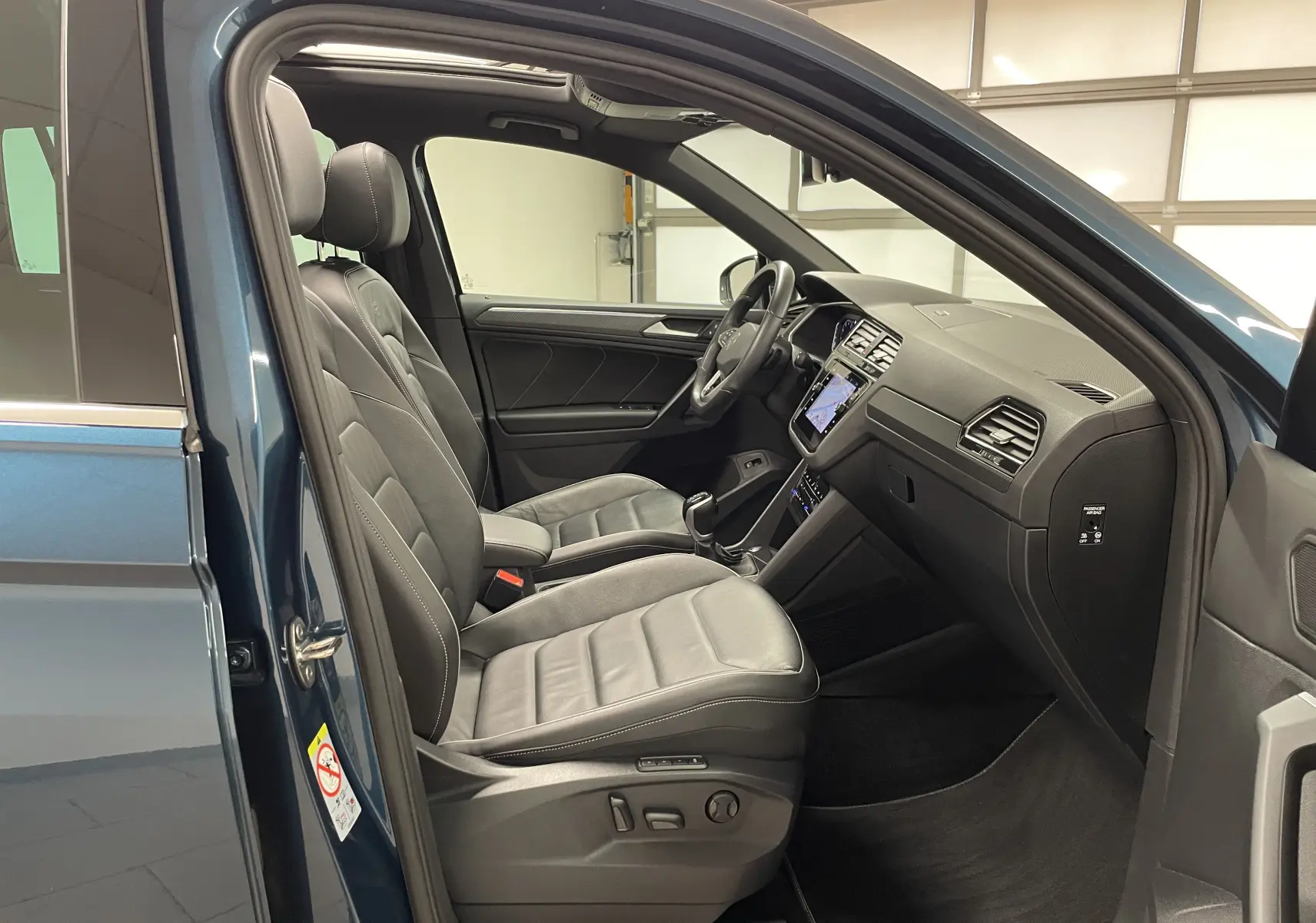 Intérieur côté conducteur du Volkswagen Tiguan 2024 bleu Nightshade, sièges cuir et tableau de bord moderne avec écran tactile.