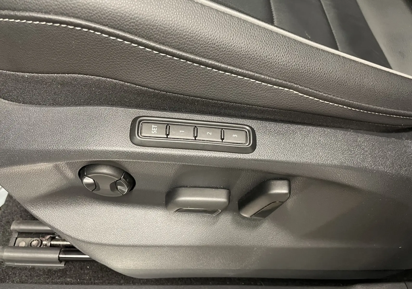 Gros plan sur les commandes de réglage électrique du siège conducteur en cuir noir du Volkswagen Tiguan Nightshade Blue 2024.