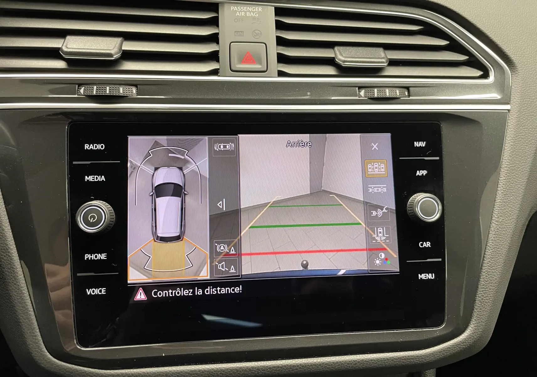 Vue rapprochée de l'écran tactile du Volkswagen Tiguan 2024 affichant la caméra de recul et l'aide au stationnement.