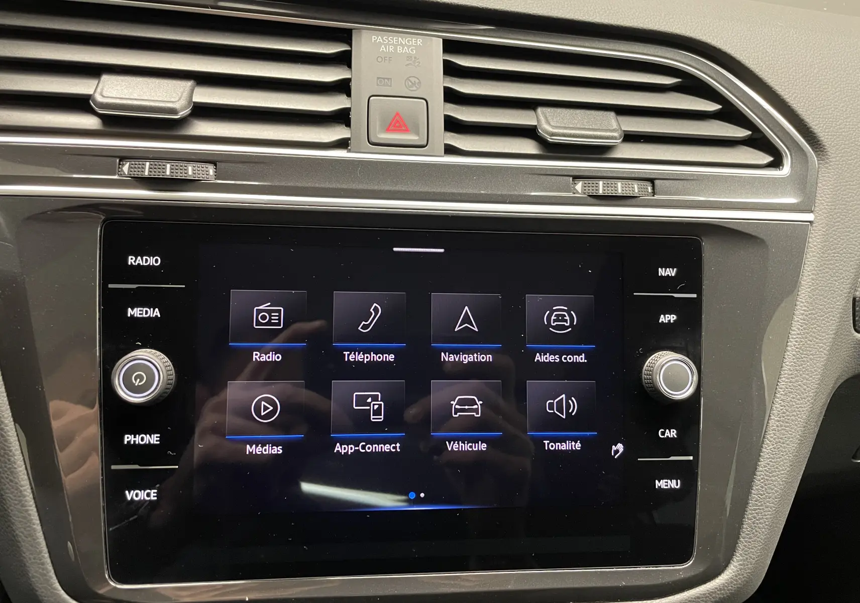 Vue rapprochée de l’écran tactile central du Volkswagen Tiguan 2024 avec menus radio, navigation et aides à la conduite visibles.