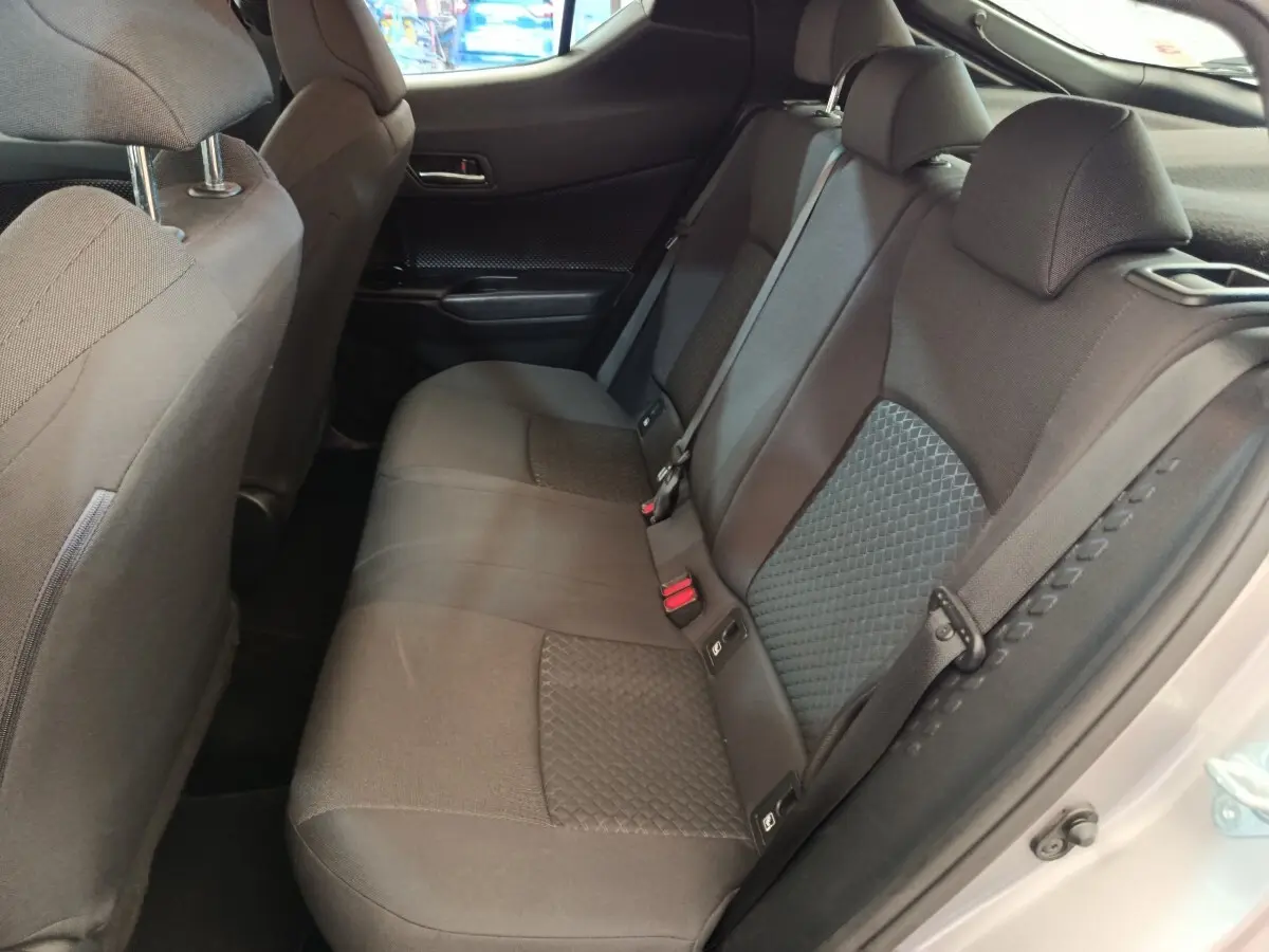 Vue côté droit de la banquette arrière grise avec appuie-têtes et ceintures de sécurité du Toyota C-HR 2.0 Hybride 184.