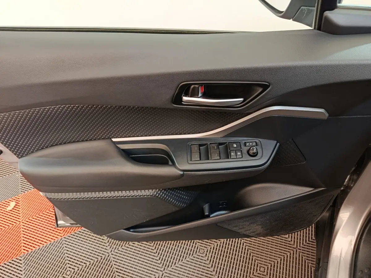 Vue rapprochée de la porte avant gauche du Toyota C-HR gris clair, avec commandes des vitres et poignée intérieure.