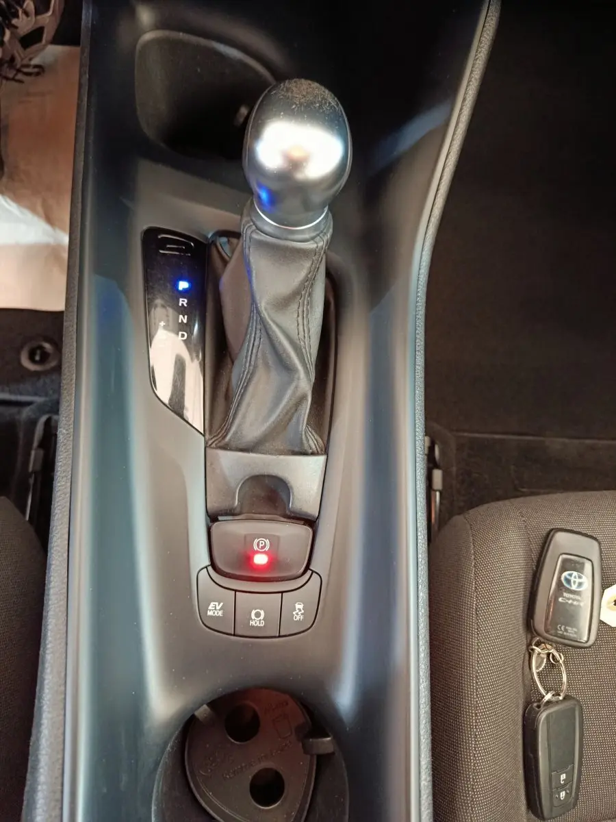 Vue plongeante sur la console centrale du Toyota C-HR hybride 2022, avec levier de vitesse et clé sur siège gris.