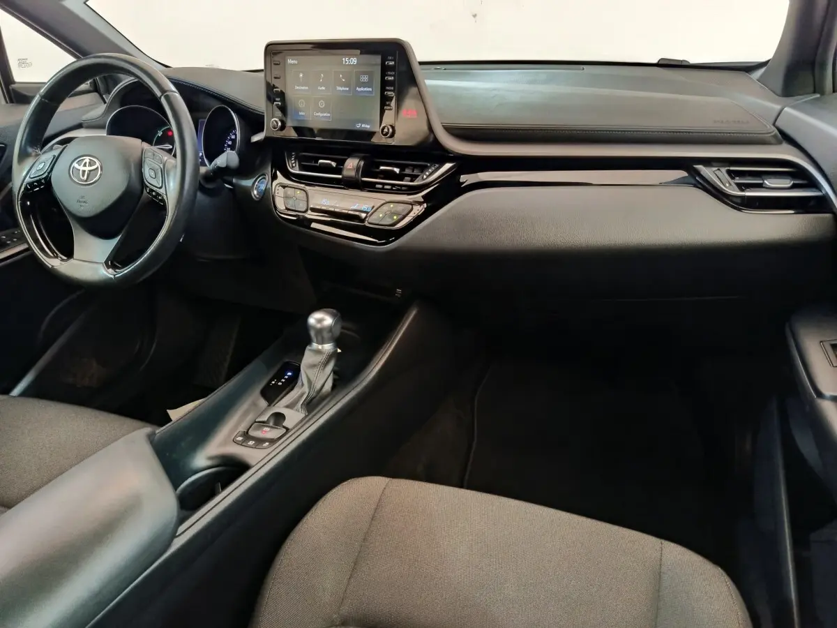 Intérieur avant du Toyota C-HR gris clair 2022, tableau de bord avec écran tactile central et volant multifonctions cuir.
