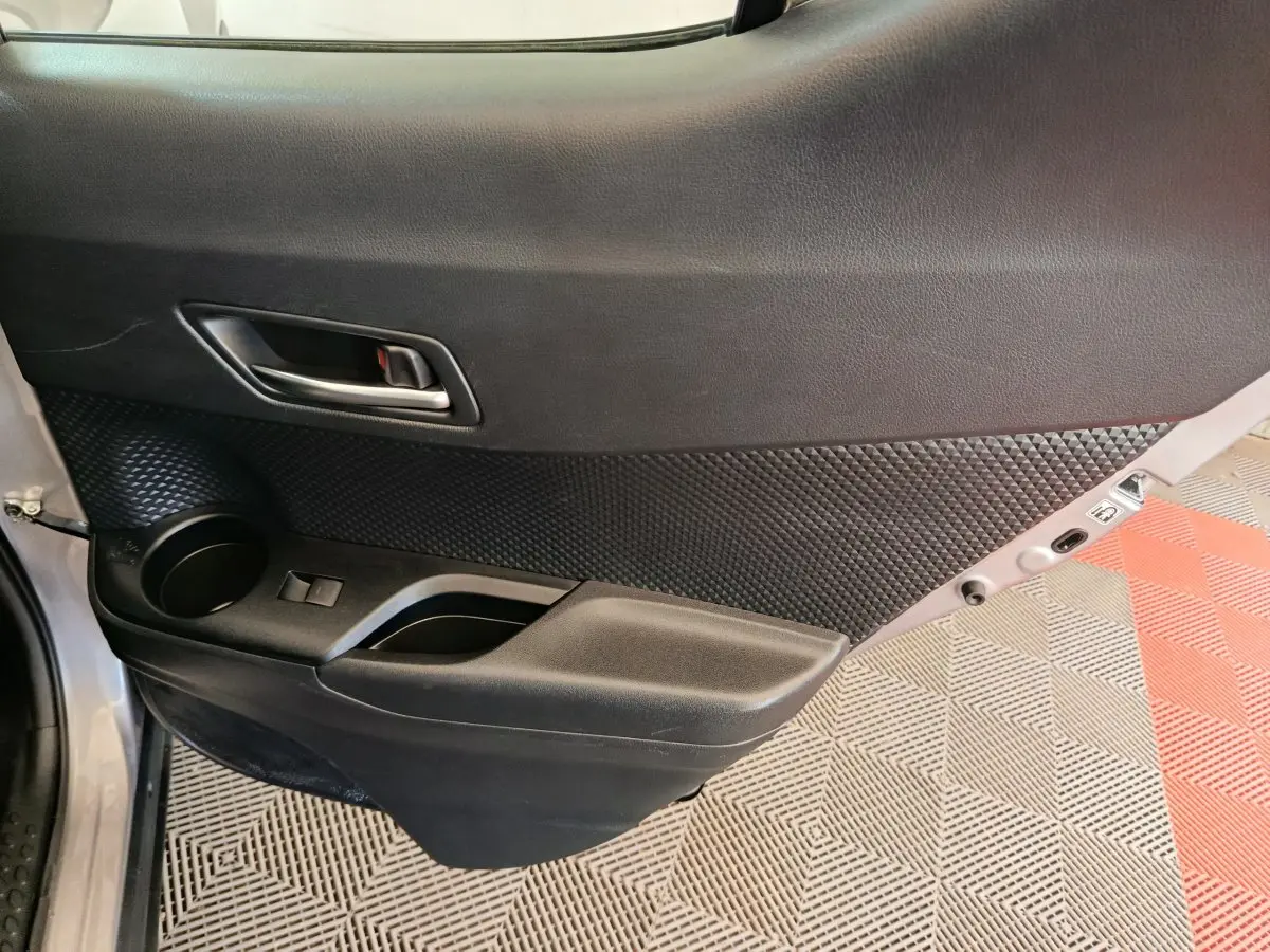 Gros plan sur la porte arrière gauche intérieure du Toyota C-HR gris clair, avec poignée et rangement intégré.