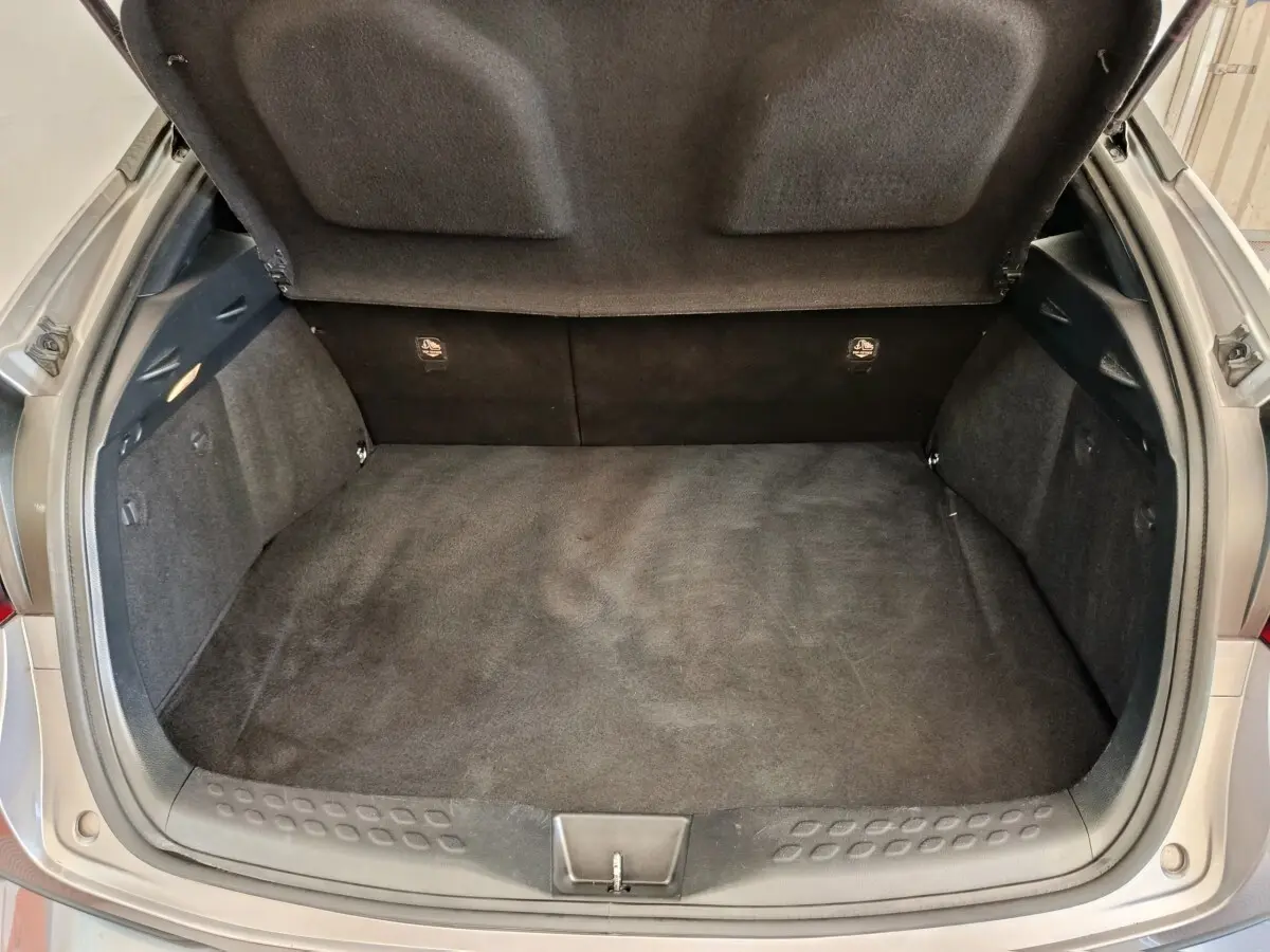Coffre ouvert vu de dessus d’un Toyota C-HR gris clair, montrant l’espace de chargement vide et la garniture intérieure.