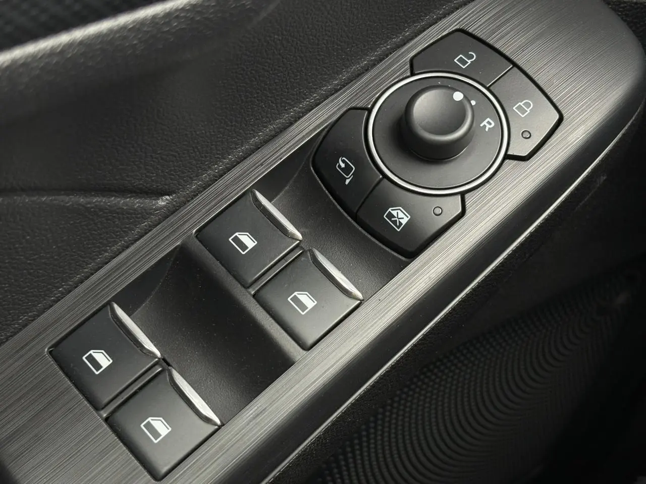 Gros plan sur les commandes de lève-vitres et rétroviseurs côté conducteur du Ford Kuga gris graphite 2023.