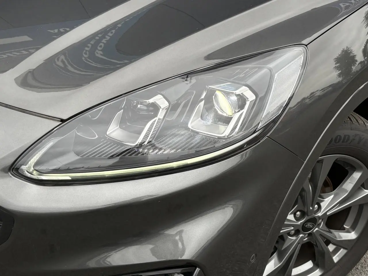 Gros plan sur le phare avant droit et la roue alliage 18 pouces gris graphite du Ford Kuga 2023 finition ST-Line.