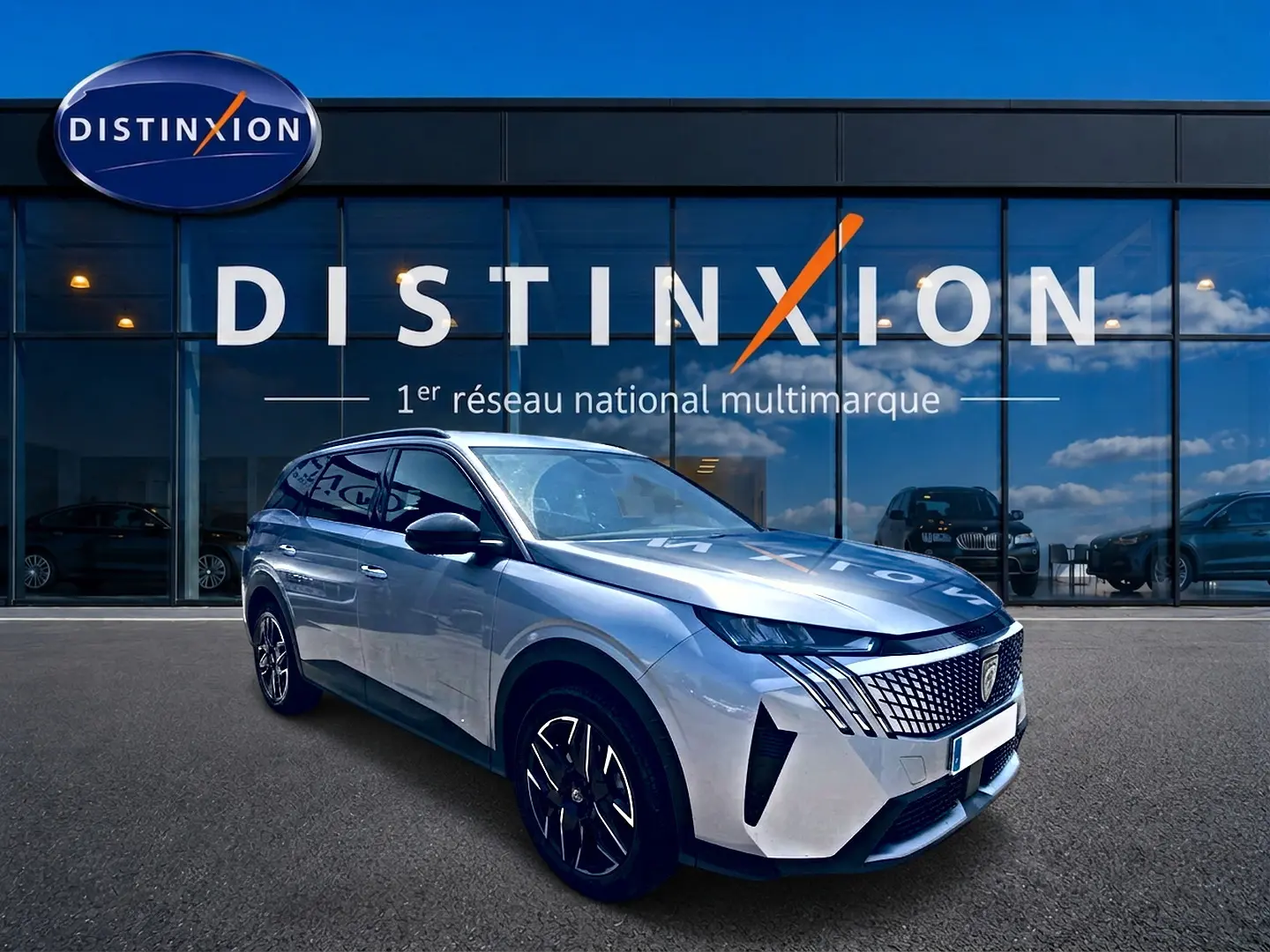 Peugeot 5008 Hybrid 145 allure e-dcs6 gris artense en 3/4 avant droit devant une vitrine Distinxion.