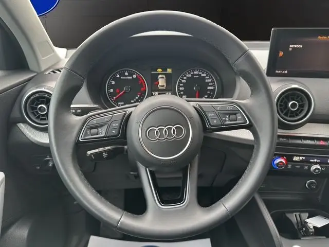 Vue centrée sur le volant noir de l'Audi Q2 35 TFSI 2023, avec tableau de bord et écran multimédia visibles.