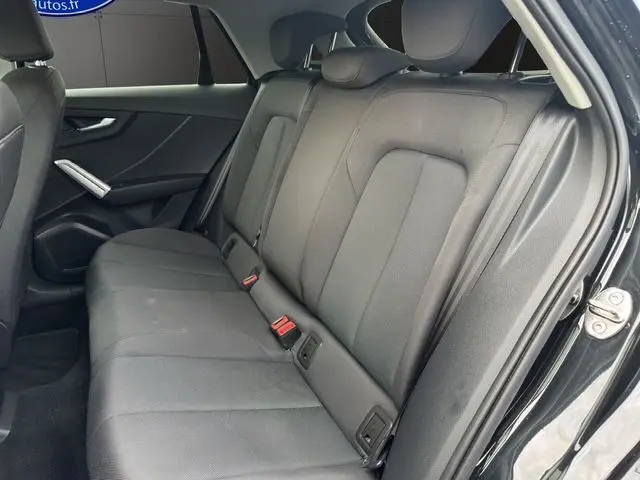 Vue intérieure côté droit des sièges arrière en tissu noir du SUV Audi Q2 noir Mito 2023 avec appuie-têtes et ceintures visibles.