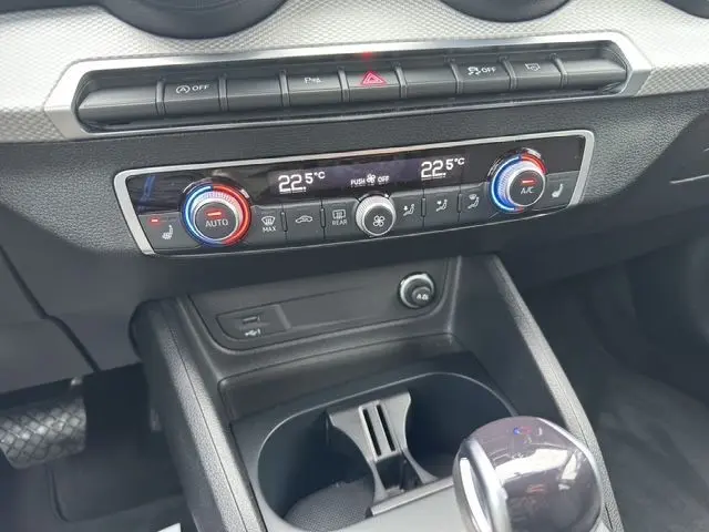 Gros plan sur la console centrale de l'Audi Q2 noir mito 2023, montrant la climatisation automatique bi-zone et le levier de vitesse.