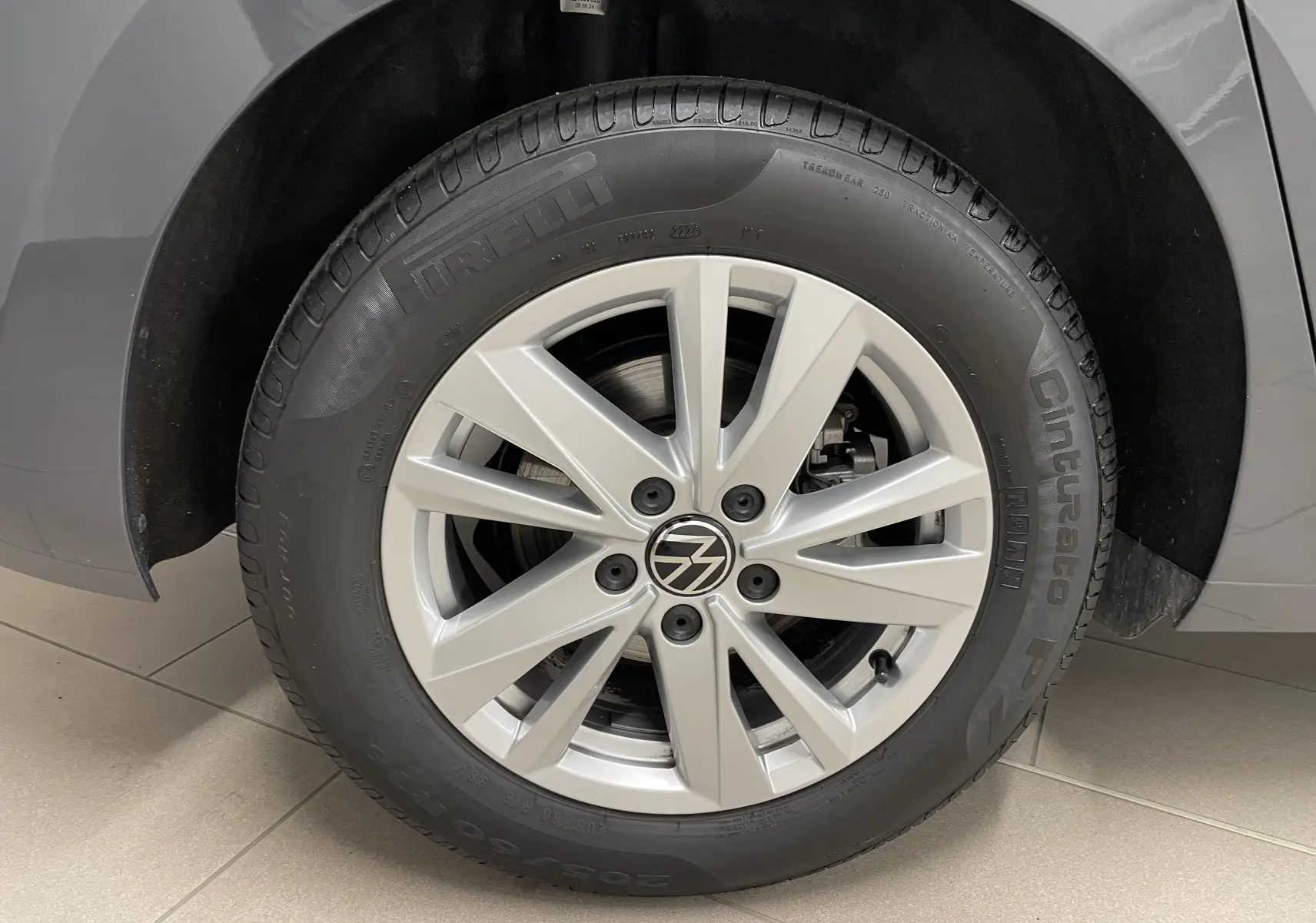 Gros plan sur la roue avant droite du Volkswagen Touran gris Dauphin 2024 avec jante alliage et pneu Pirelli.