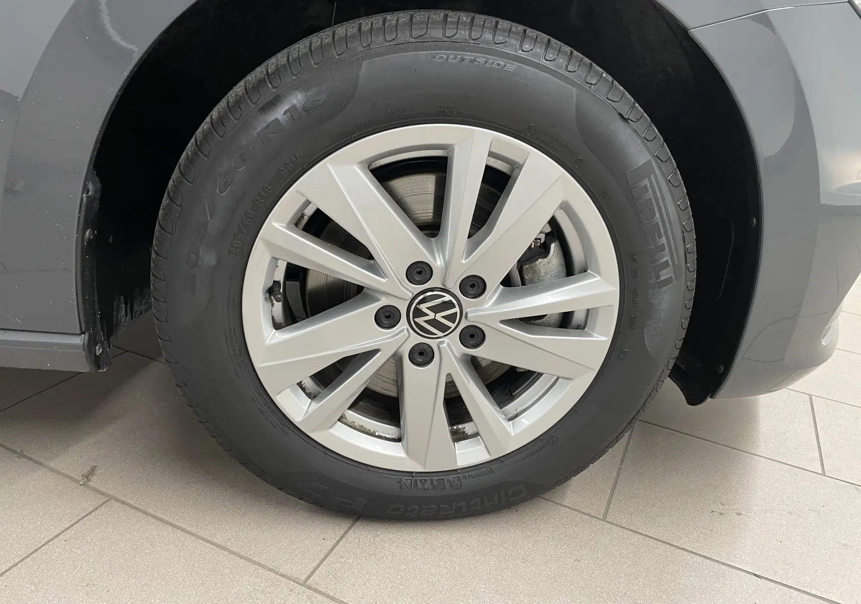 Gros plan sur la roue avant gauche d'un Volkswagen Touran gris dauphin avec jante alliage et pneu Pirelli