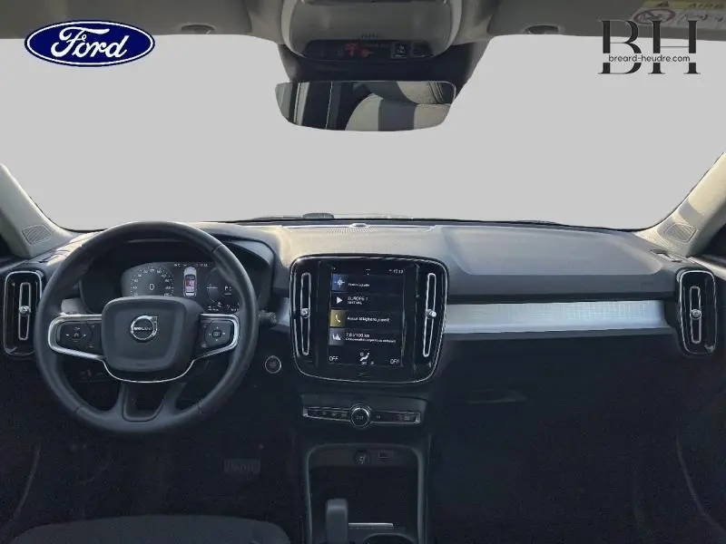 Vue intérieure frontale du tableau de bord noir du Volvo XC40 T5 Recharge avec écran tactile central et volant multifonction.