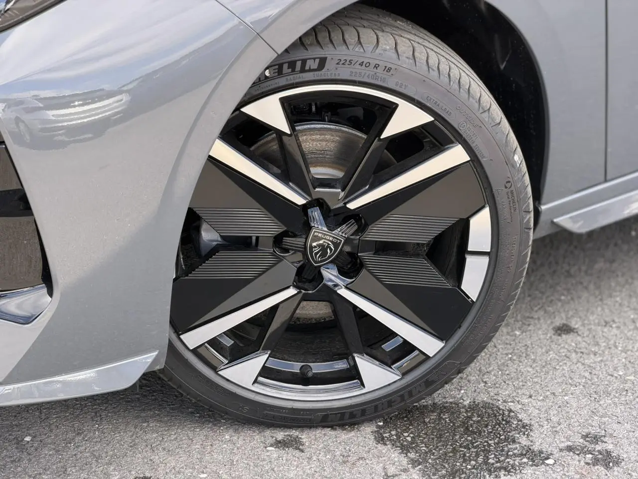Gros plan sur la jante alliage bi-tons noir et argent de la Peugeot 308 gris Selenium, roue avant côté gauche.
