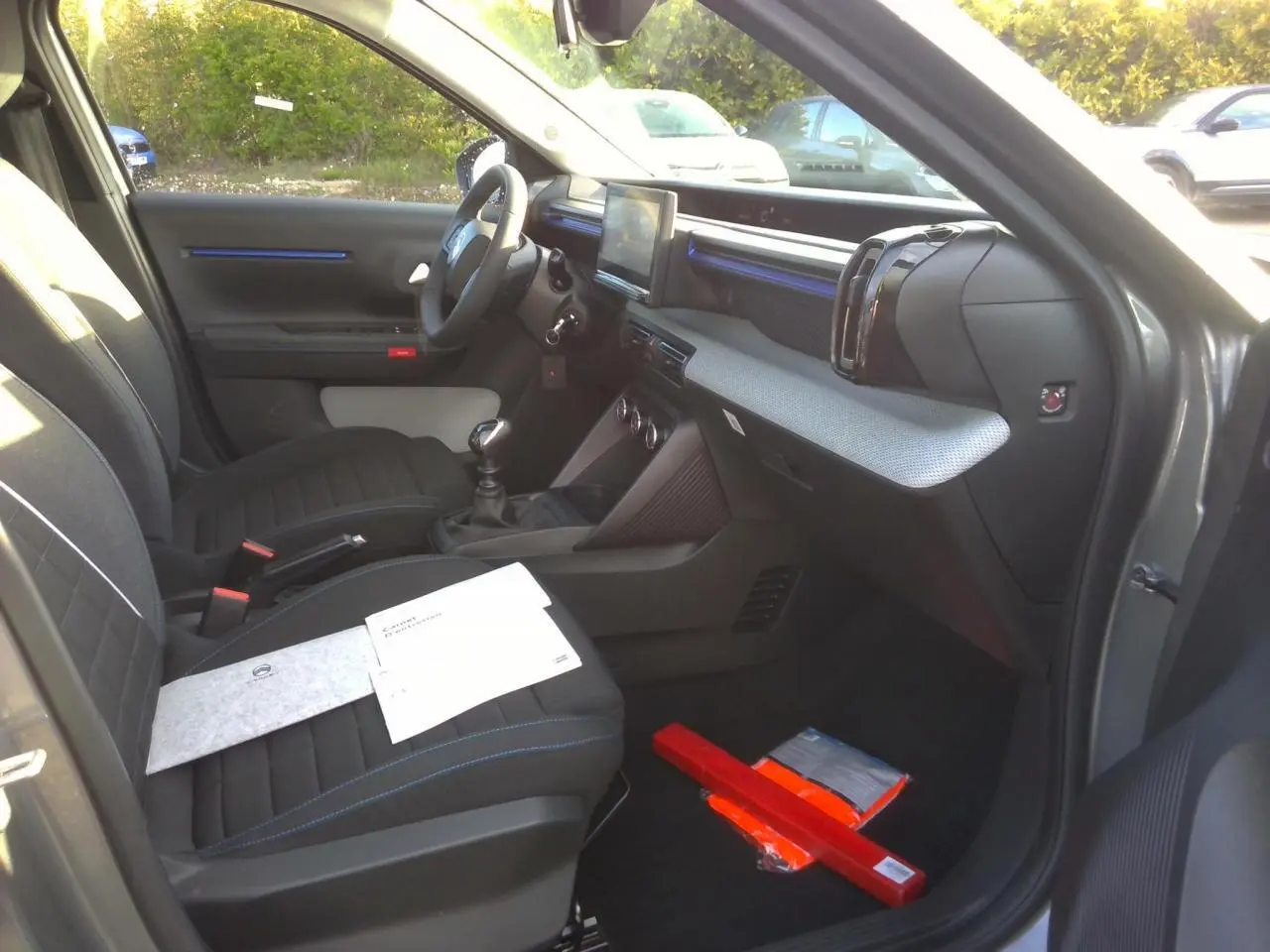Vue intérieure côté passager avant d'une Citroën C3 gris foncé 2025, avec sièges noirs et détails bleu Ultra Blue.