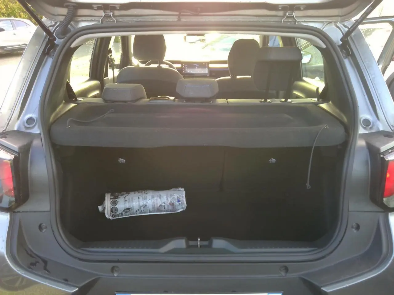 Vue arrière du coffre ouvert d'une Citroën C3 gris foncé, montrant l'espace de chargement et la plage arrière.