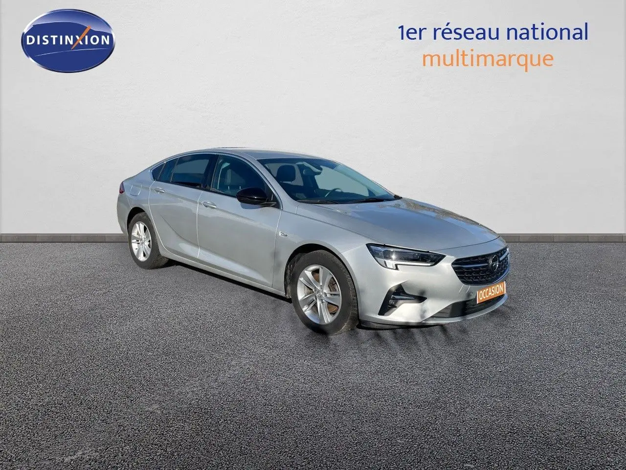 Opel Insignia gris minéral métal vue 3/4 avant droit, avec calandre noire et jantes argentées.