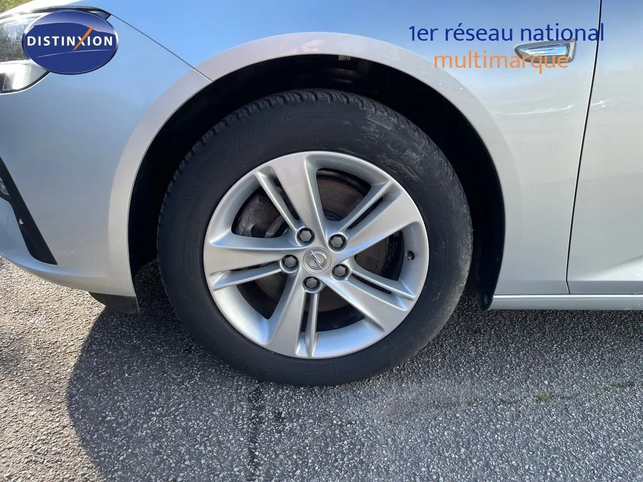 Gros plan sur la roue avant gauche d'une Opel Insignia gris minéral métal, mettant en valeur la jante alliage.