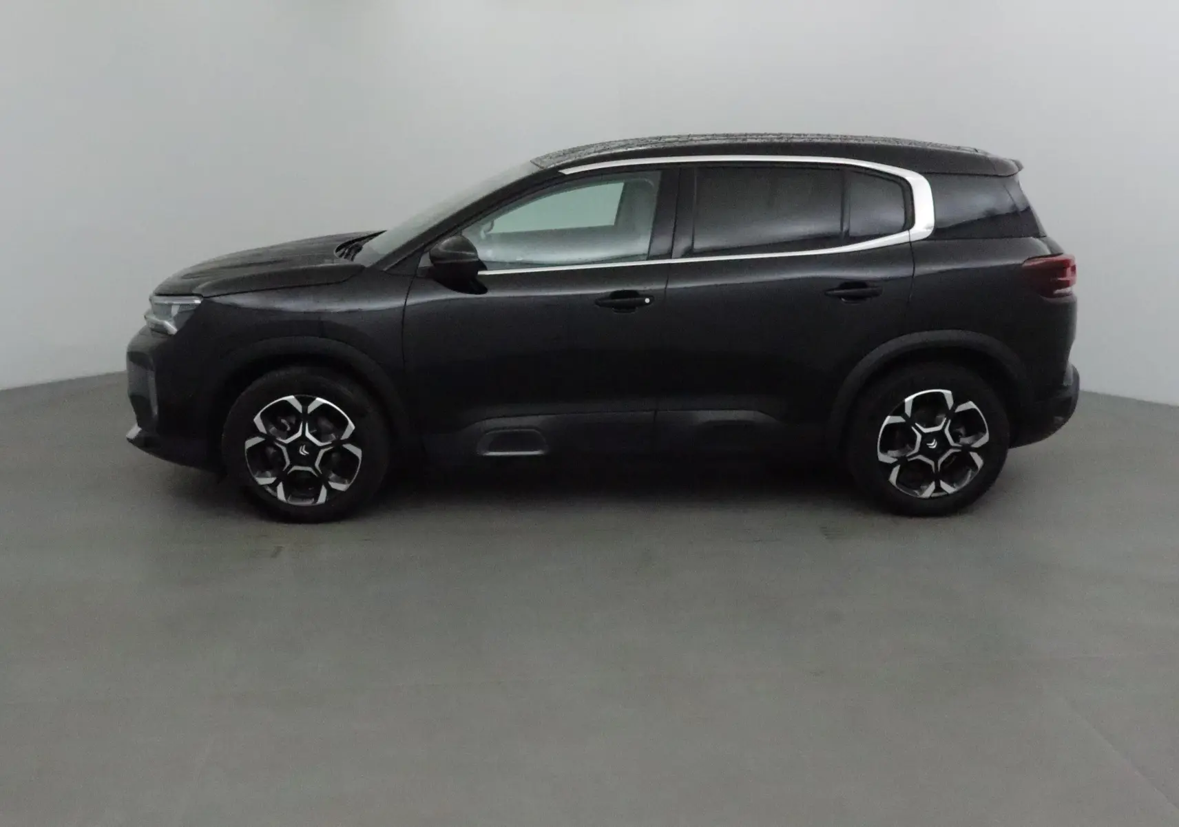 Profil côté gauche d'un Citroën C5 Aircross noir 2024 avec jantes alliage et cadre de vitre chromé.