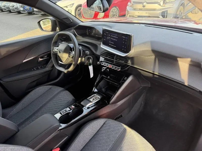 Vue intérieure avant droite du Peugeot 2008 1.2 Hybrid 136ch Allure avec tableau de bord moderne et sièges tissu gris.