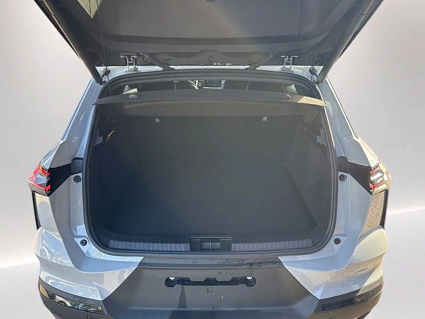 Vue arrière du coffre ouvert du Renault Symbioz gris rafale, mettant en valeur l'espace de chargement.