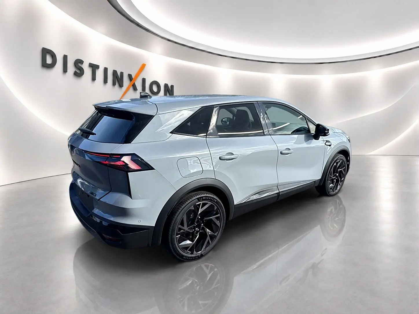 Renault Symbioz gris rafale en vue 3/4 arrière droit, avec jantes noires et toit noir contrasté dans un showroom lumineux.