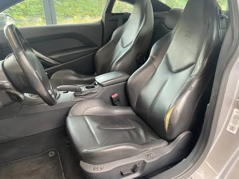 Vue intérieure côté conducteur de la Peugeot RCZ 1.6 THP 2010 avec sièges sport cuir noirs et volant cuir.