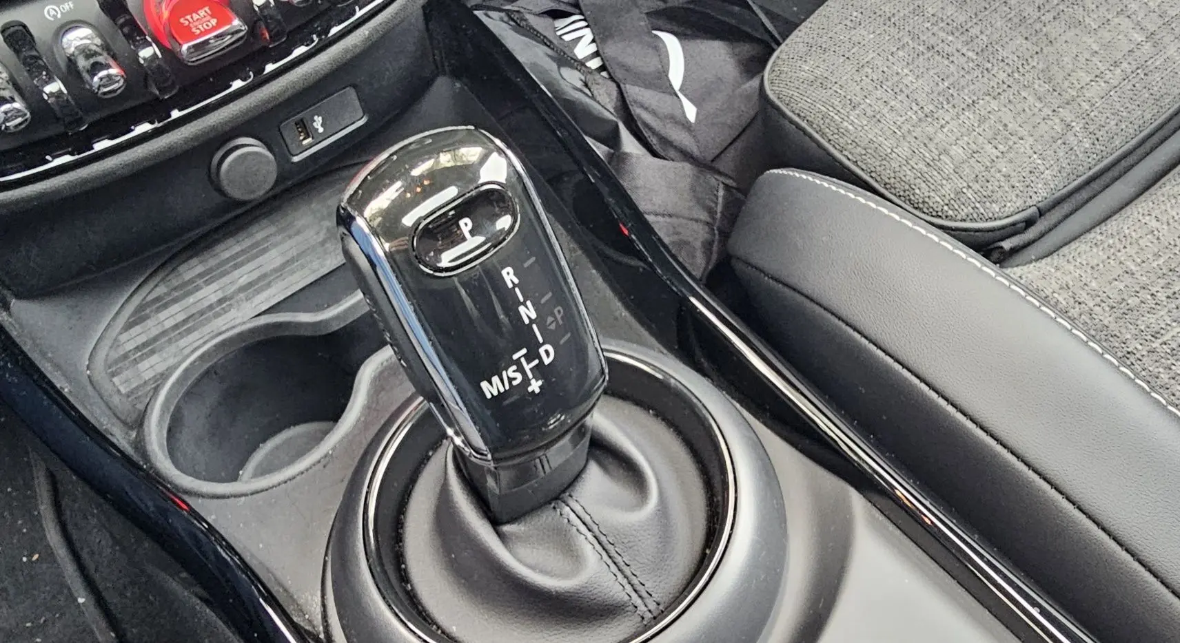 Le levier de vitesses automatique noir brillant de la MINI Cooper S Clubman 2022, entouré de la console centrale et siège gris.