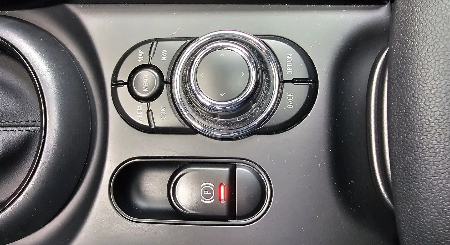 Gros plan sur la molette de commande multimédia et le frein à main électronique rouge dans l'habitacle noir de la MINI Cooper S Clubman 2022.