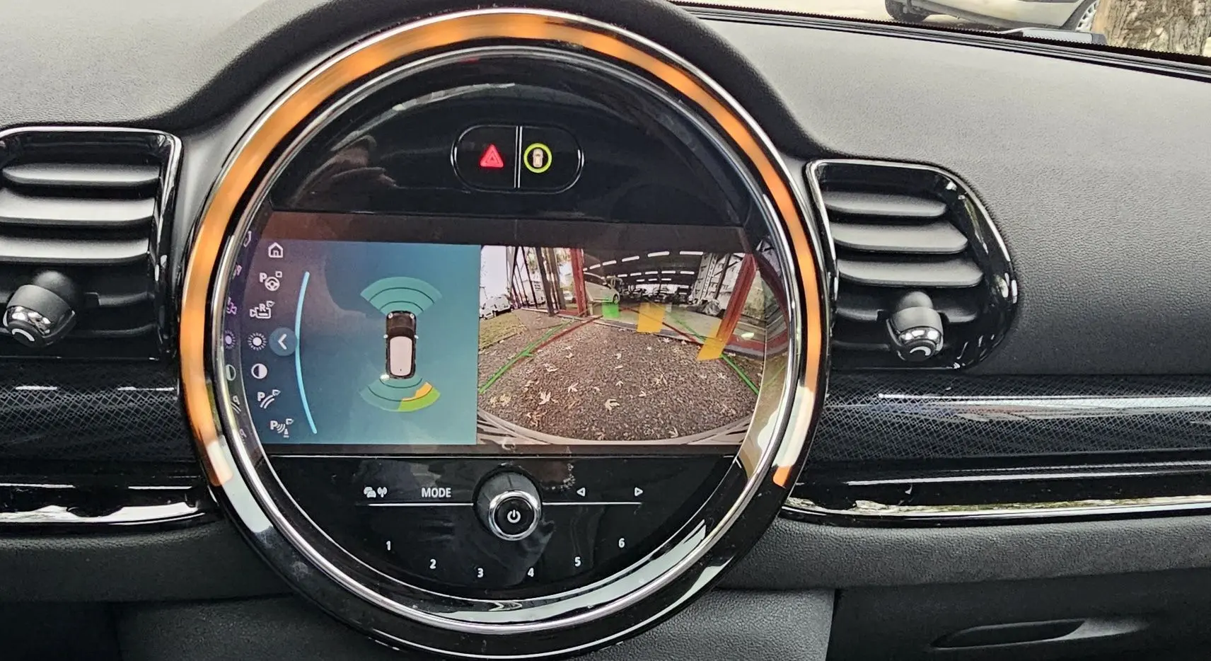 Écran central rond affichant la caméra de recul et les capteurs de stationnement dans une MINI Clubman grise de 2022.