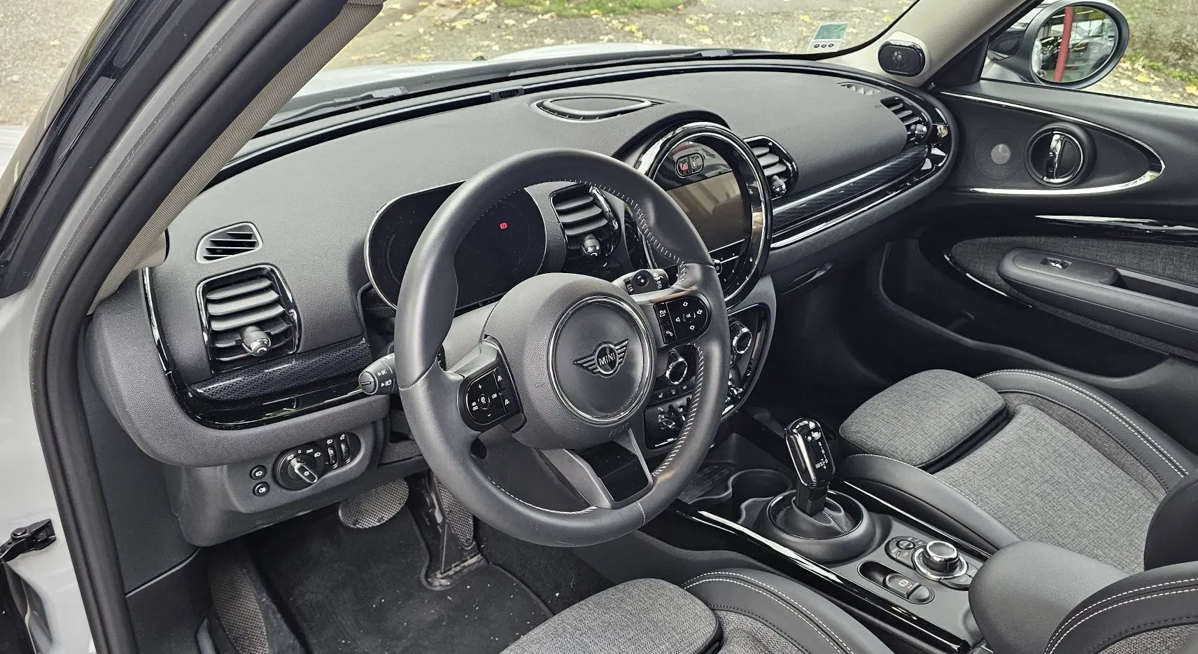 Intérieur côté conducteur d'une MINI Clubman grise 2022, avec tableau de bord noir et sellerie tissu gris.