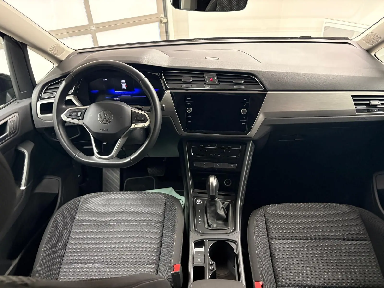 Intérieur avant du Volkswagen Touran 2024 avec tableau de bord moderne et volant multifonction noir.