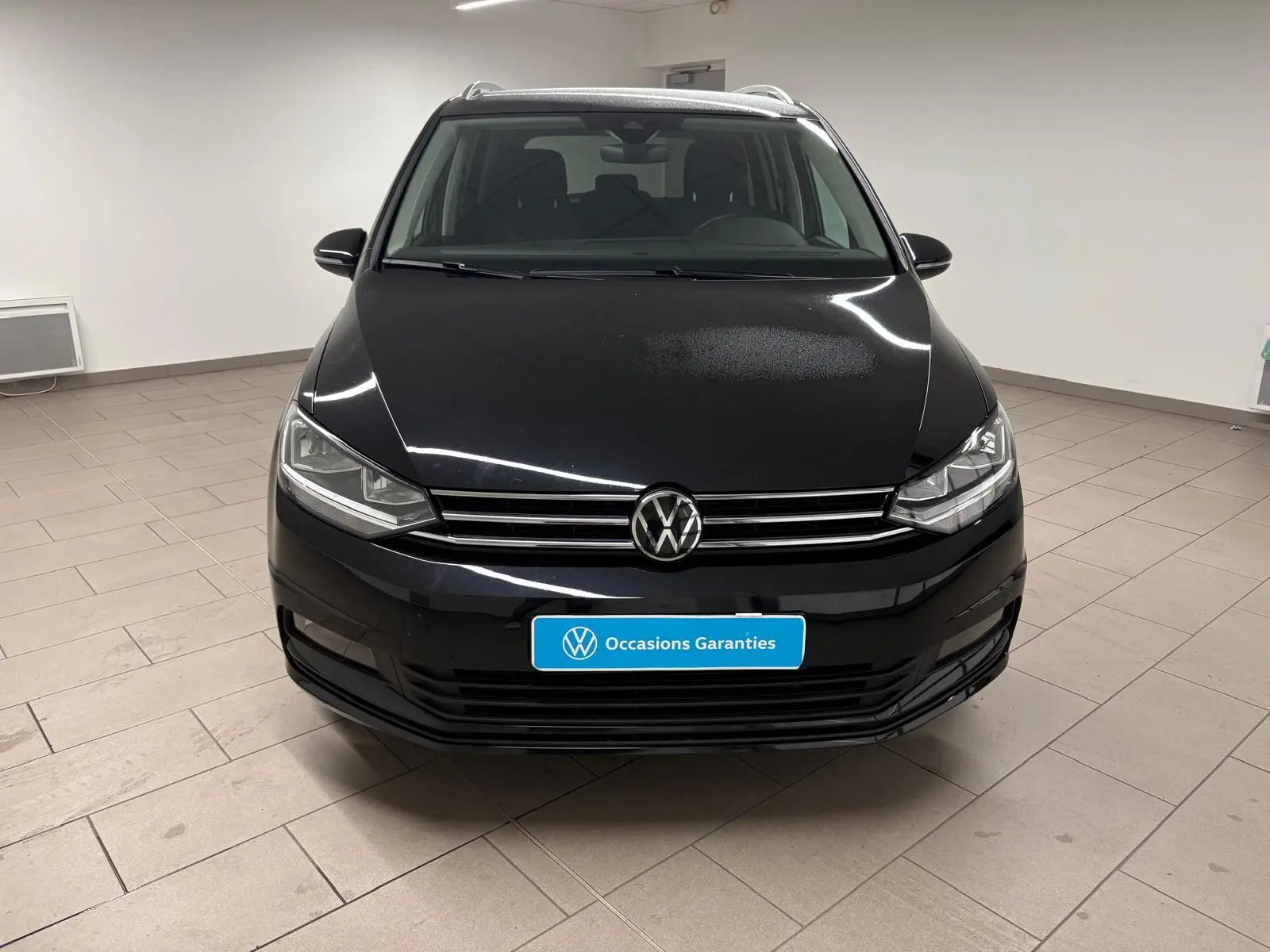 Volkswagen Touran noir intense nacré vu de face, mettant en valeur la calandre et les phares LED.