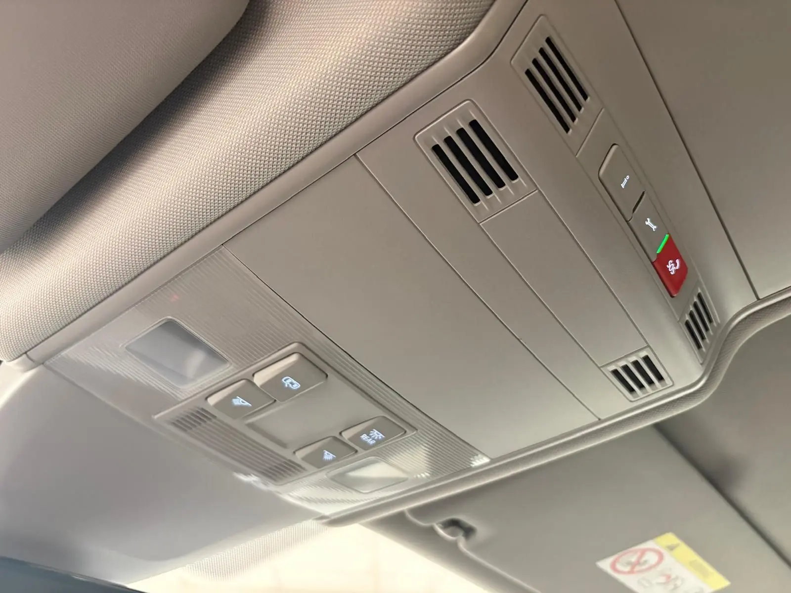 Plafonnier intérieur gris clair du Volkswagen Touran 2024 avec commandes d'éclairage et ventilation intégrées.