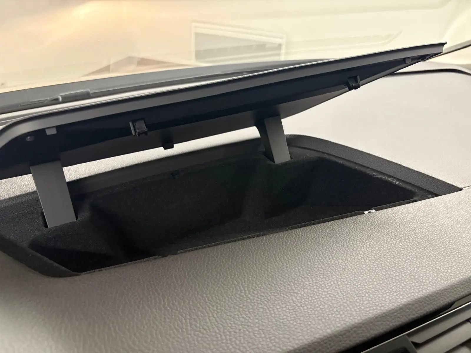 Rangement ouvert sur le tableau de bord du Volkswagen Touran 2024 noir intense nacré, vue intérieure rapprochée.