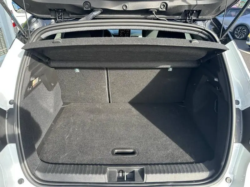 Coffre ouvert vu de l'arrière du Renault Captur blanc nacré, montrant l'espace de rangement intérieur noir.