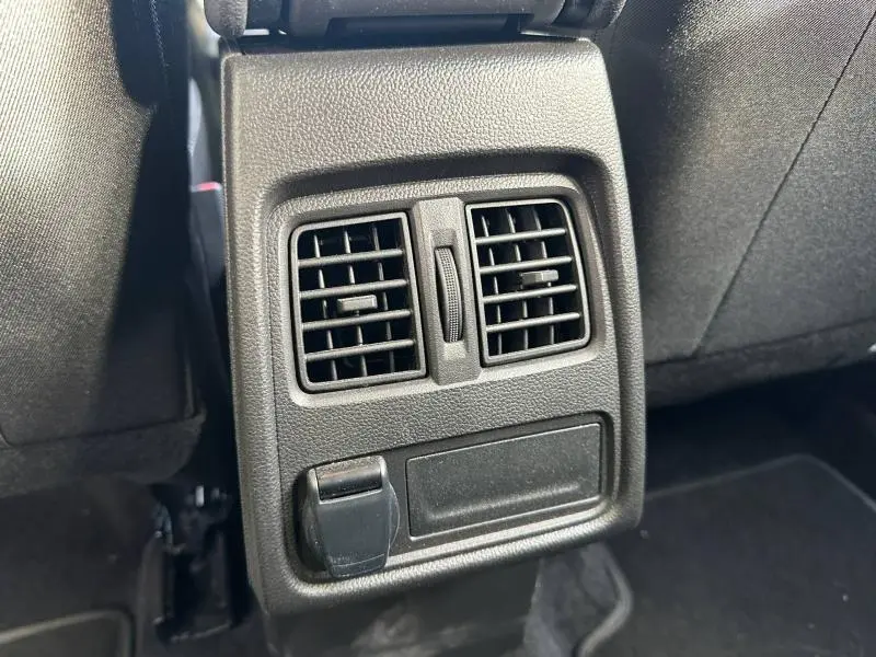 Gros plan sur les aérateurs arrière noirs et prise 12V dans l'habitacle du Renault Captur blanc nacré/noir 2025.