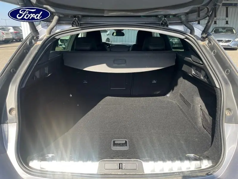 Coffre ouvert vu de l'arrière d'un Peugeot 508 SW gris Artense, avec cache-bagages et intérieur noir.