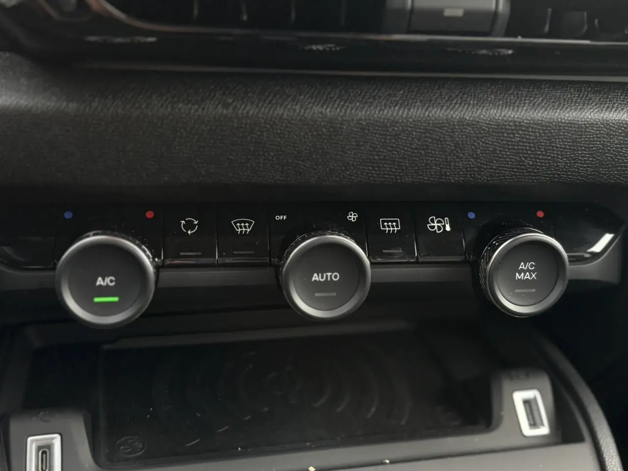 Détail de la console centrale avec commandes de climatisation automatique et recharge sans fil dans une Citroën C4 Hybrid gris Mercury.