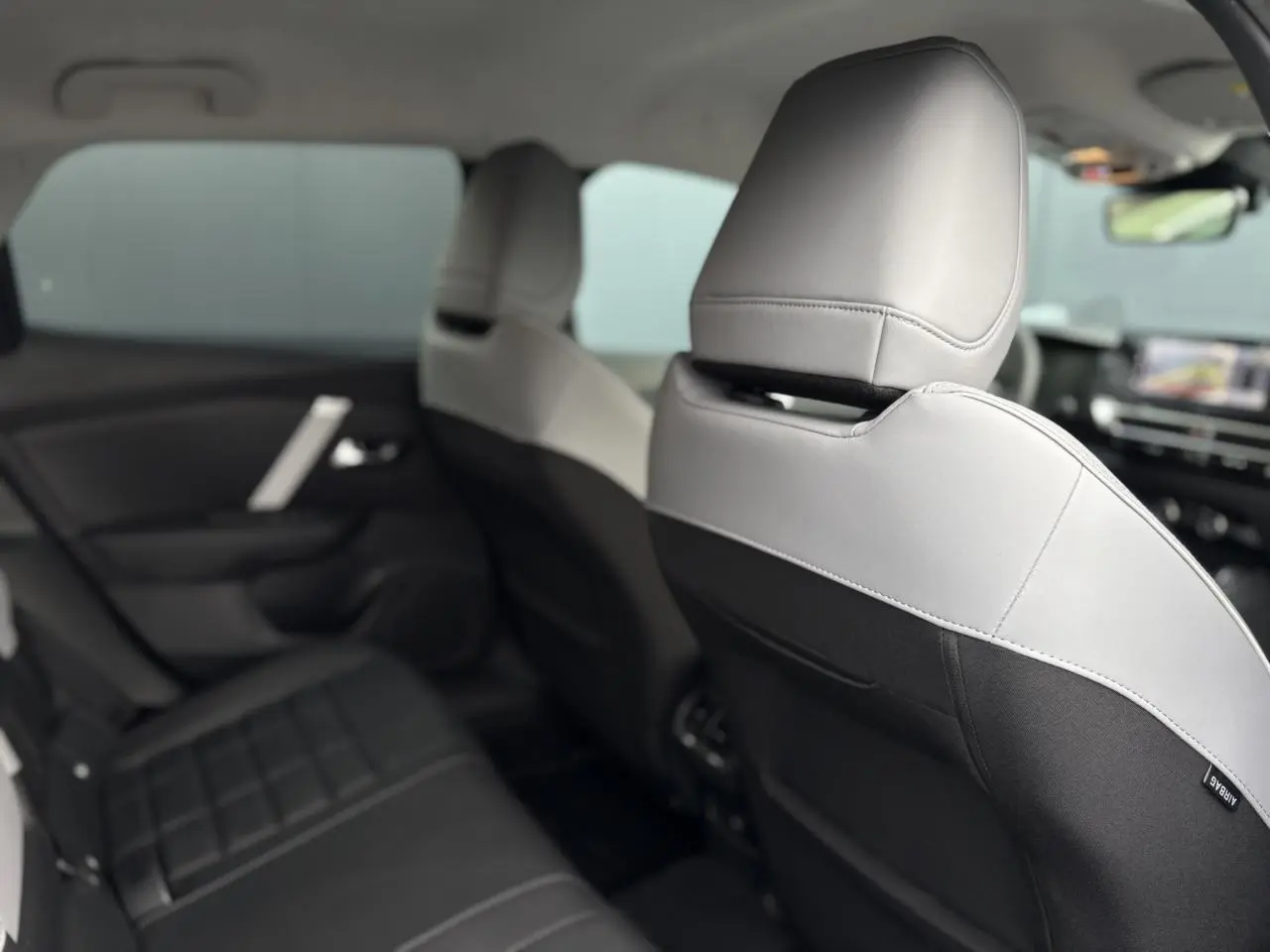 Vue intérieure arrière montrant les sièges bicolores gris clair et noir du Citroën C4 Hybrid 2025.